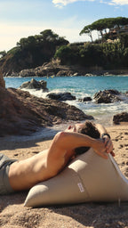 Sobre la arena, el Cojín Madeira de De Galei invita al descanso. Su tono beige integral refleja la esencia natural y serena del Mediterráneo.